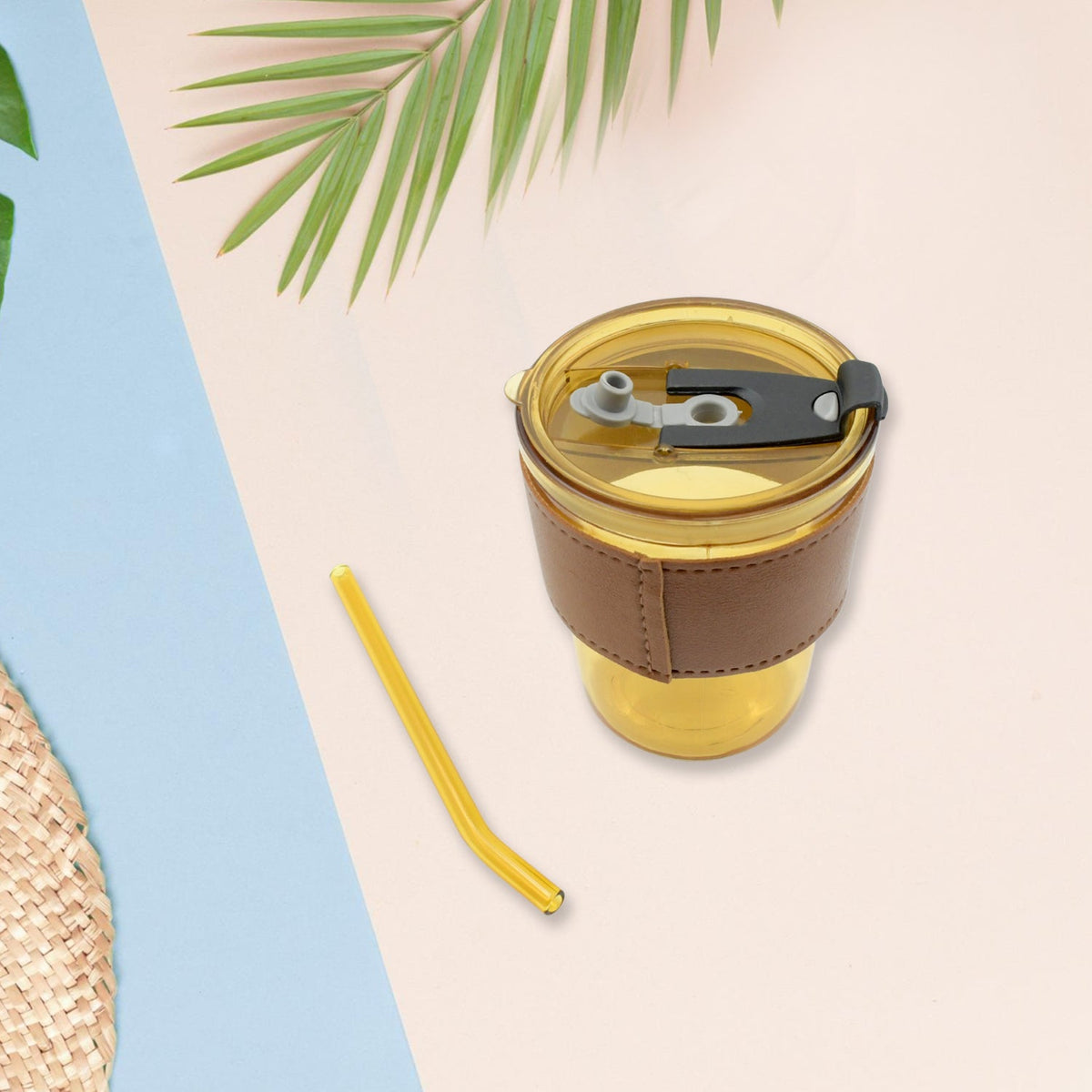Amber glass cup with sleeve and straw on patterned background