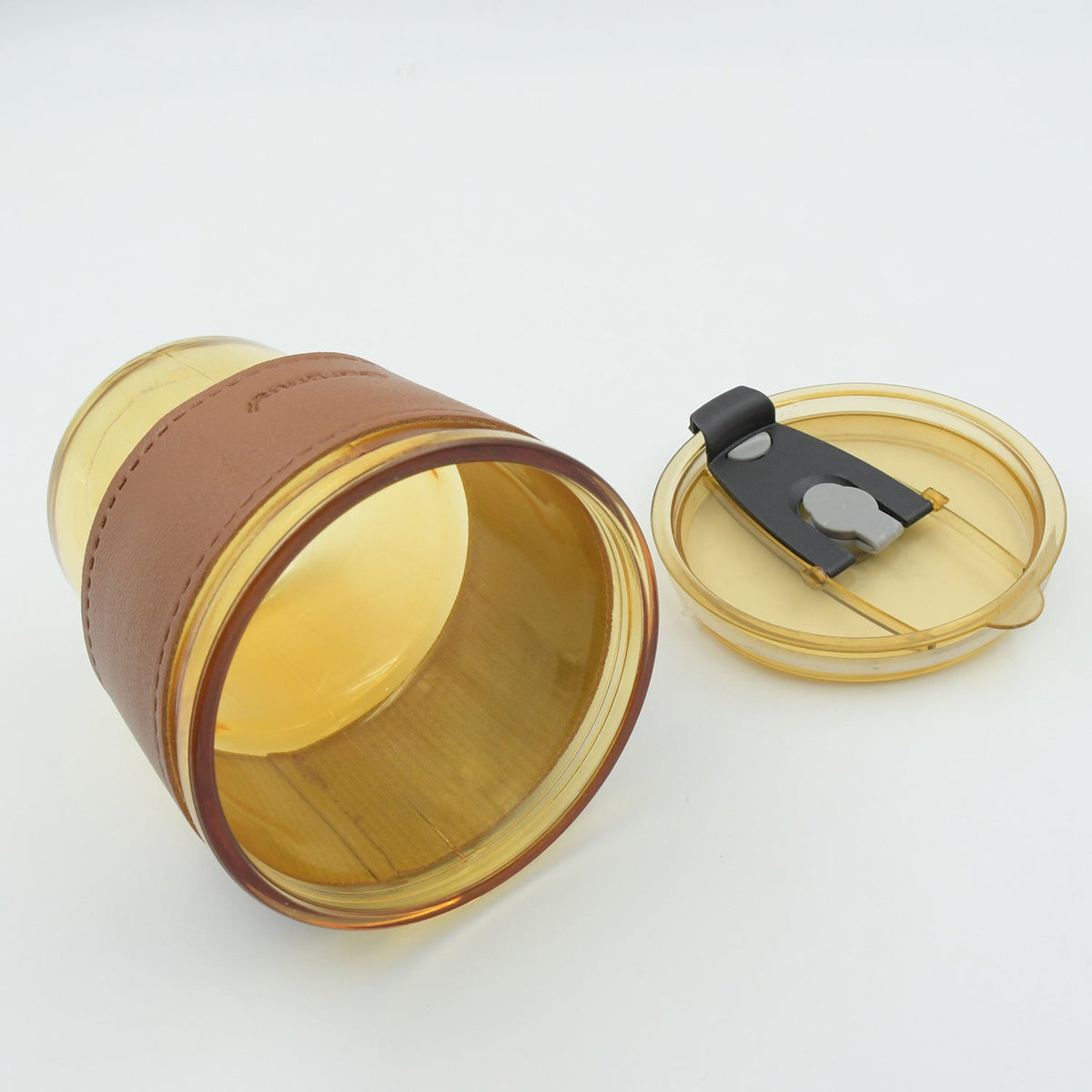 Amber glass cup with sleeve lying beside its lid